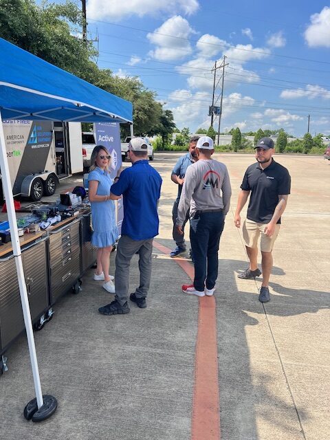 A group of people standing around an outdoor food stand.