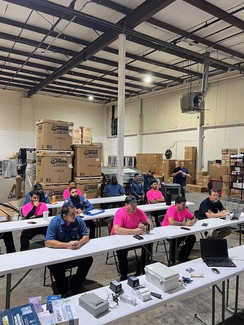 A group of people sitting at tables in a warehouse.