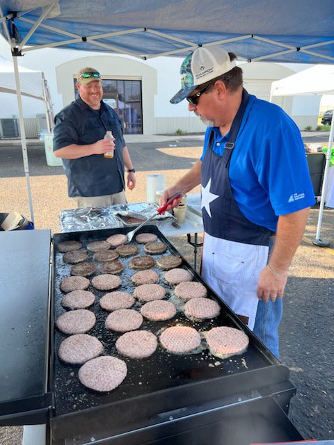 A man cooking hamburgers on an outdoor grill.